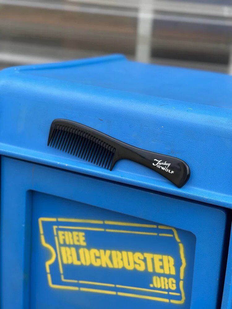 A black comb with Turkey and the Wolf branding on a bright blue textured surface.