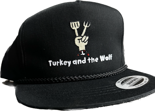 A black Turkey and the Wolf snapback hat with a fork and knife graphic, against a white background.