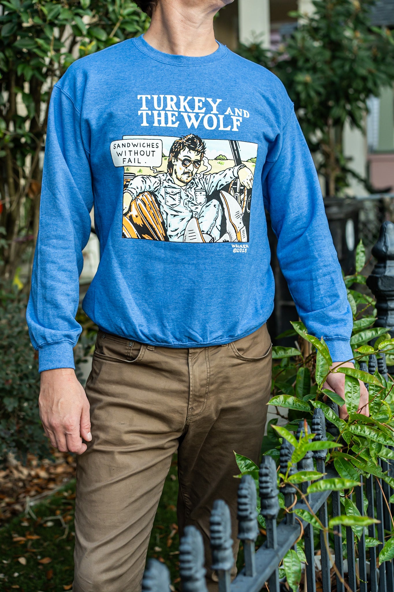 Person wearing a blue sweatshirt with a graphic design in an outdoor setting