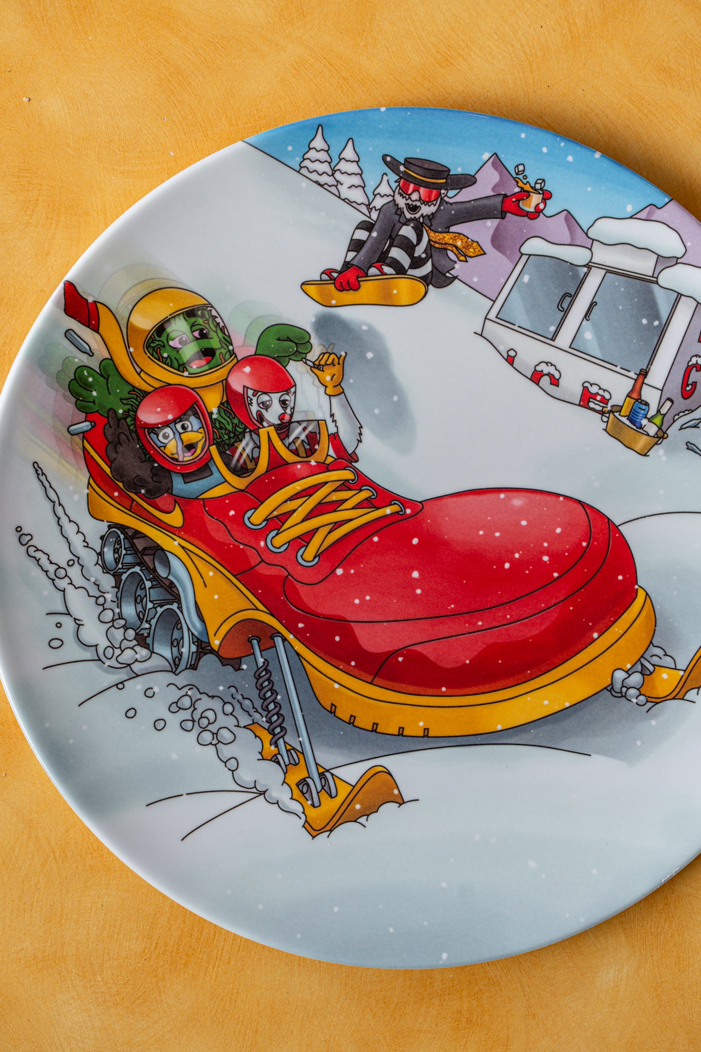 Decorative plate with a cartoon design of a red snowmobile and people on a mountain.