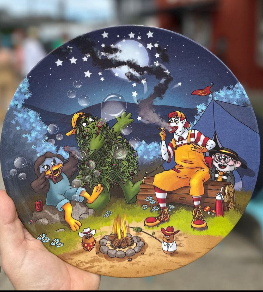 A plate with a cartoon of people camping out, featuring tents, a campfire, and a starry night sky.