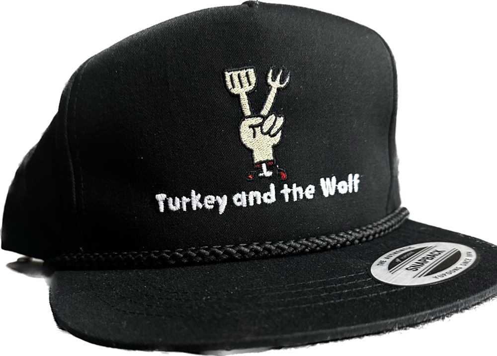 A black Turkey and the Wolf snapback hat with a fork and knife graphic, against a white background.