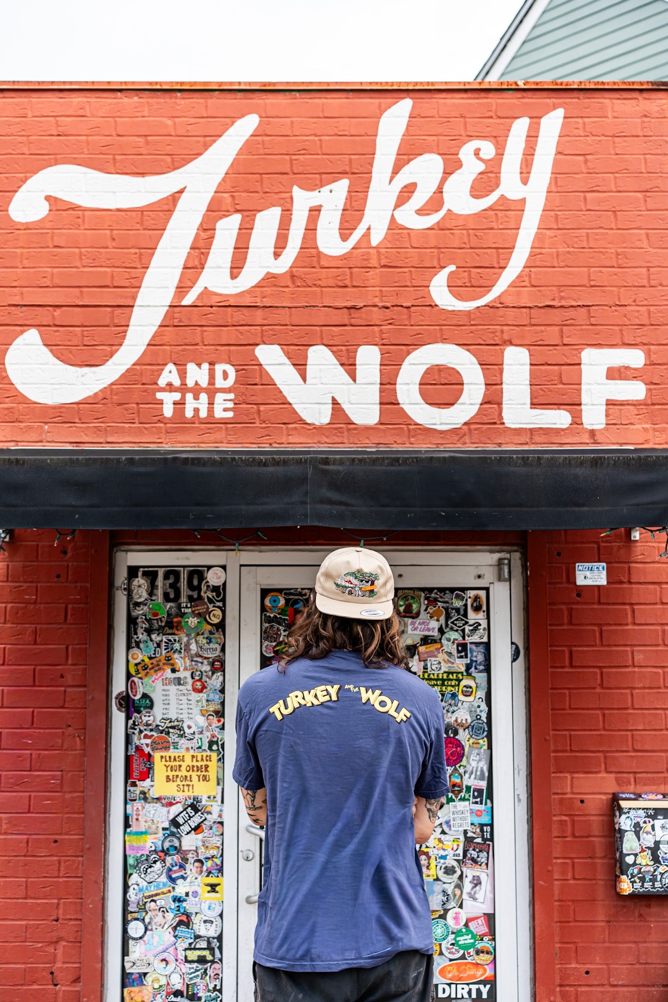 Person wearing a 'Turkey and the Wolf' shirt standing in front of a store with the same name.