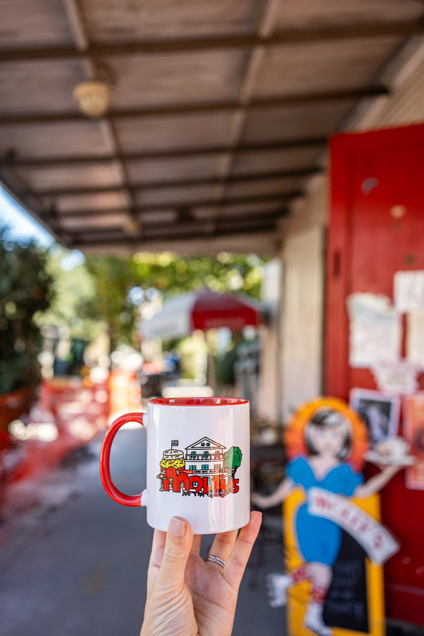 Person holding a mug with a colorful design in an outdoor setting