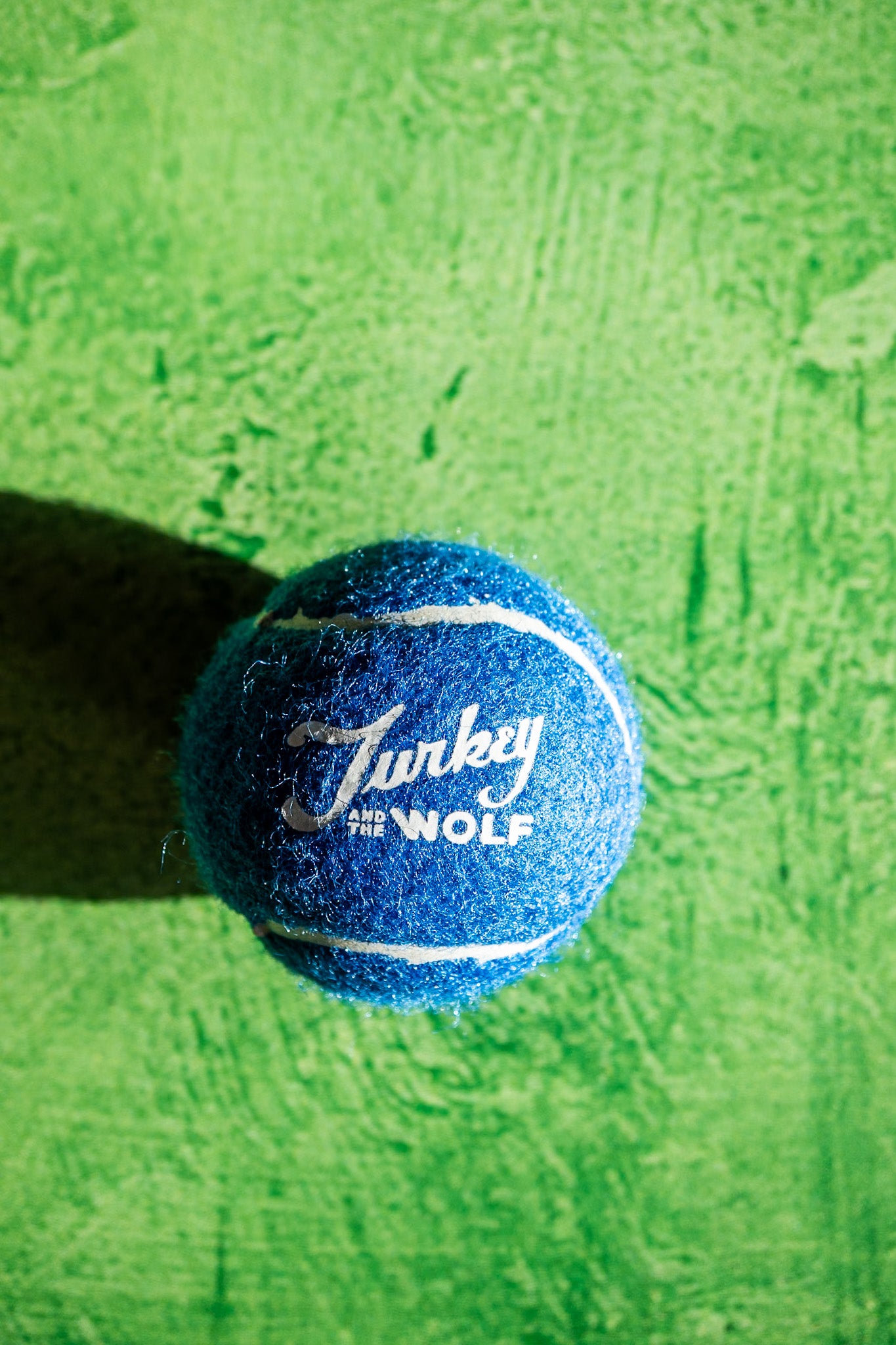 Blue tennis ball with 'Turkey the Wolf' branding on a green textured background
