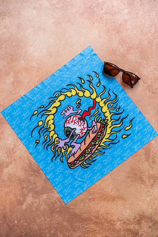 Blue towel with a colorful design on a brown surface, accompanied by sunglasses.