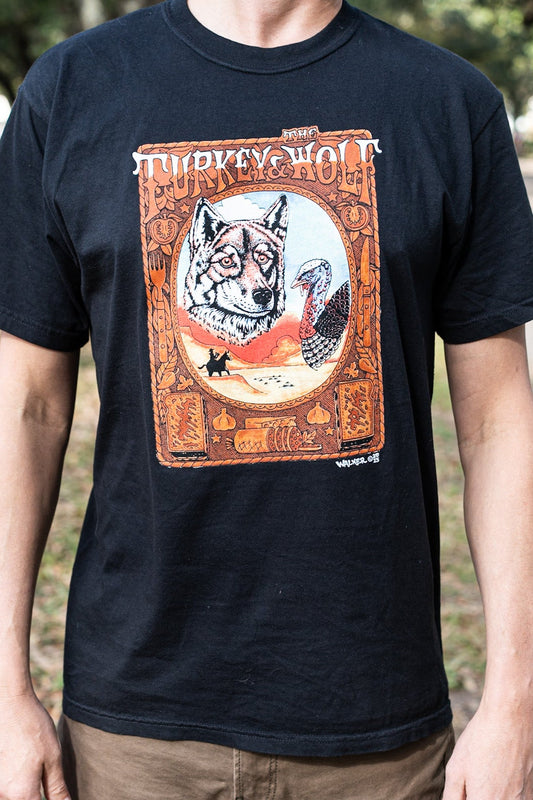 Person wearing a black t-shirt with a graphic design of a wolf and text outdoors.