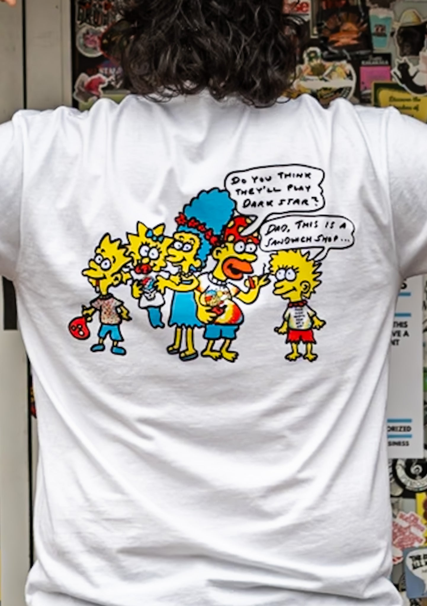 White t-shirt with colorful cartoon family design on the back, worn by a person.