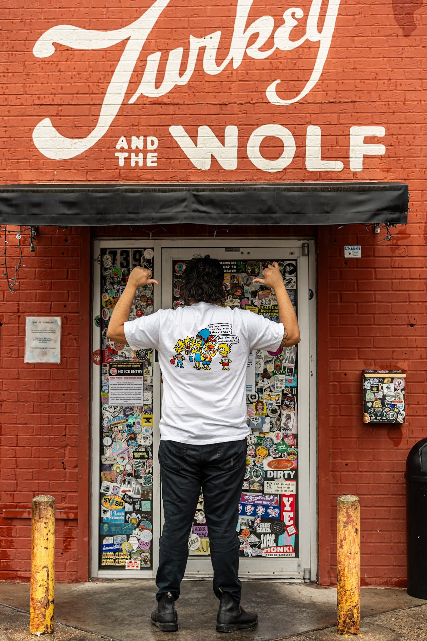Person standing in front of a store with 'Turkey and the Wolf' sign on a red brick wall.