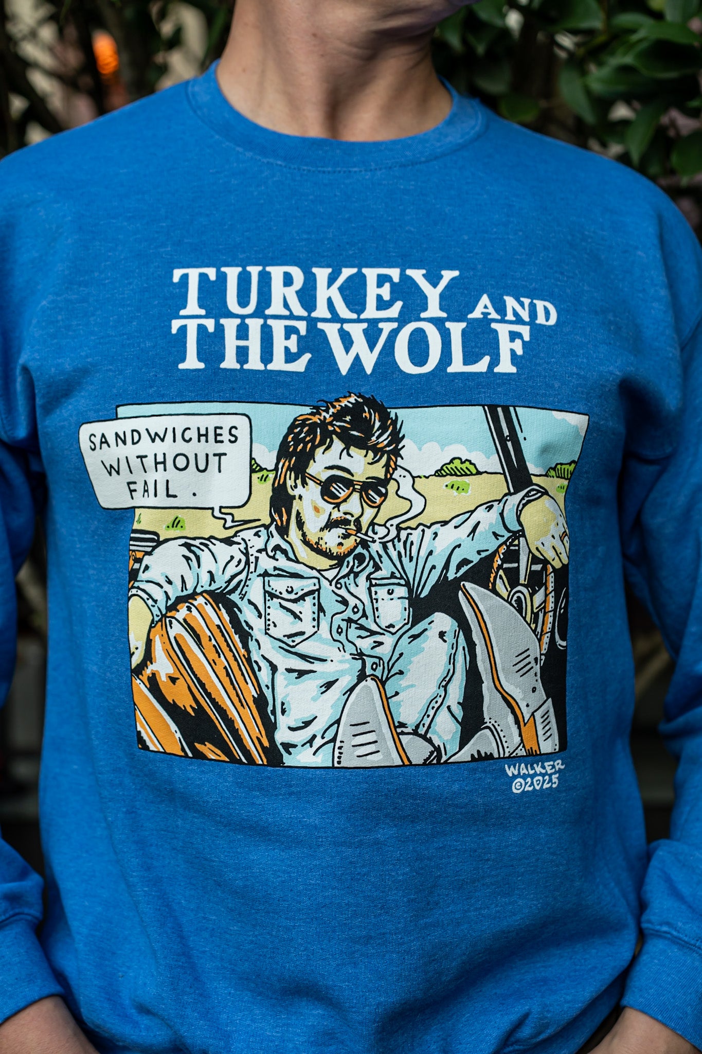 Blue sweatshirt with 'Turkey and the Wolf' graphic design featuring a person and text.