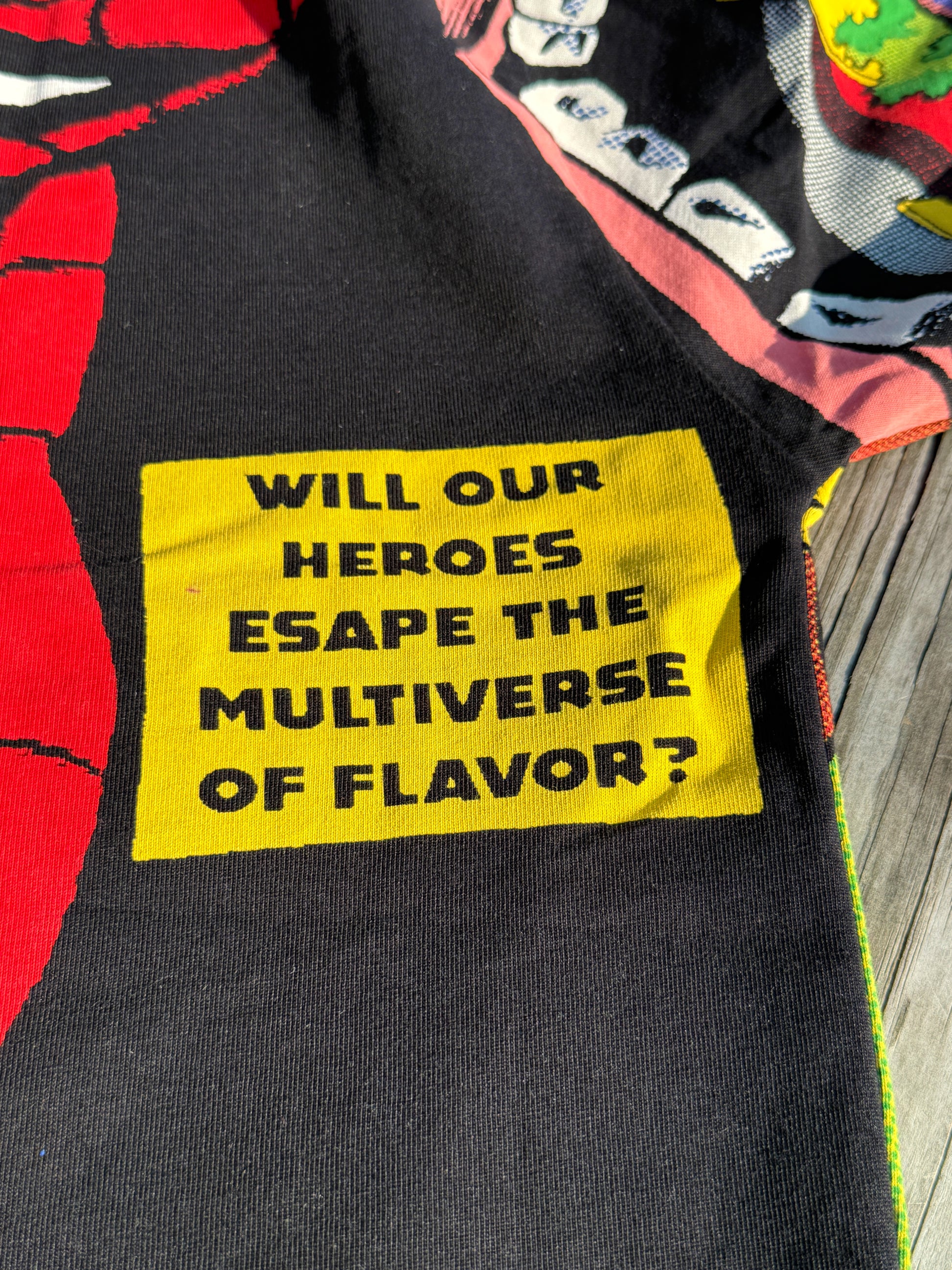 Black shirt with a yellow patch featuring text on a colorful background