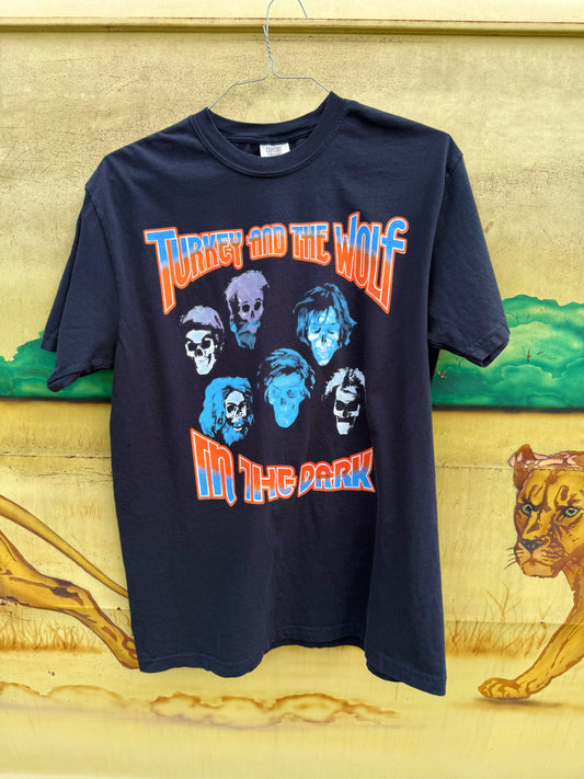 Black t-shirt with graphic design and text on a textured wall background