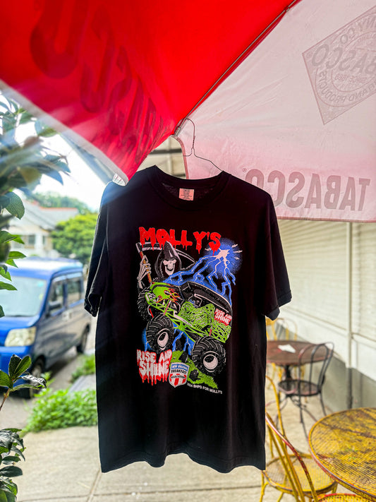 Black t-shirt with colorful graphic design held by a person outdoors under an umbrella
