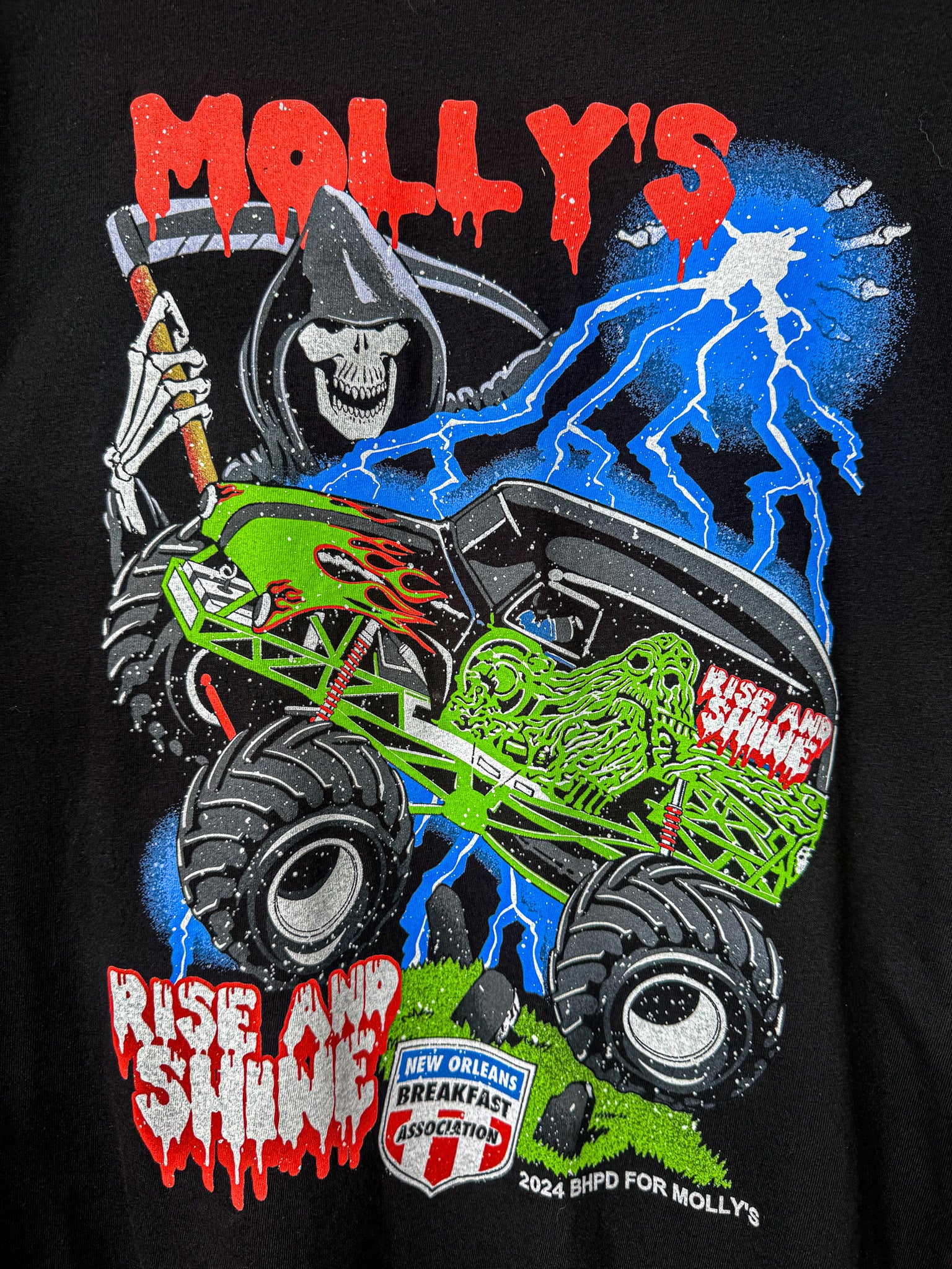 Black t-shirt with a colorful graphic of a monster truck, skeleton, and text on a black background