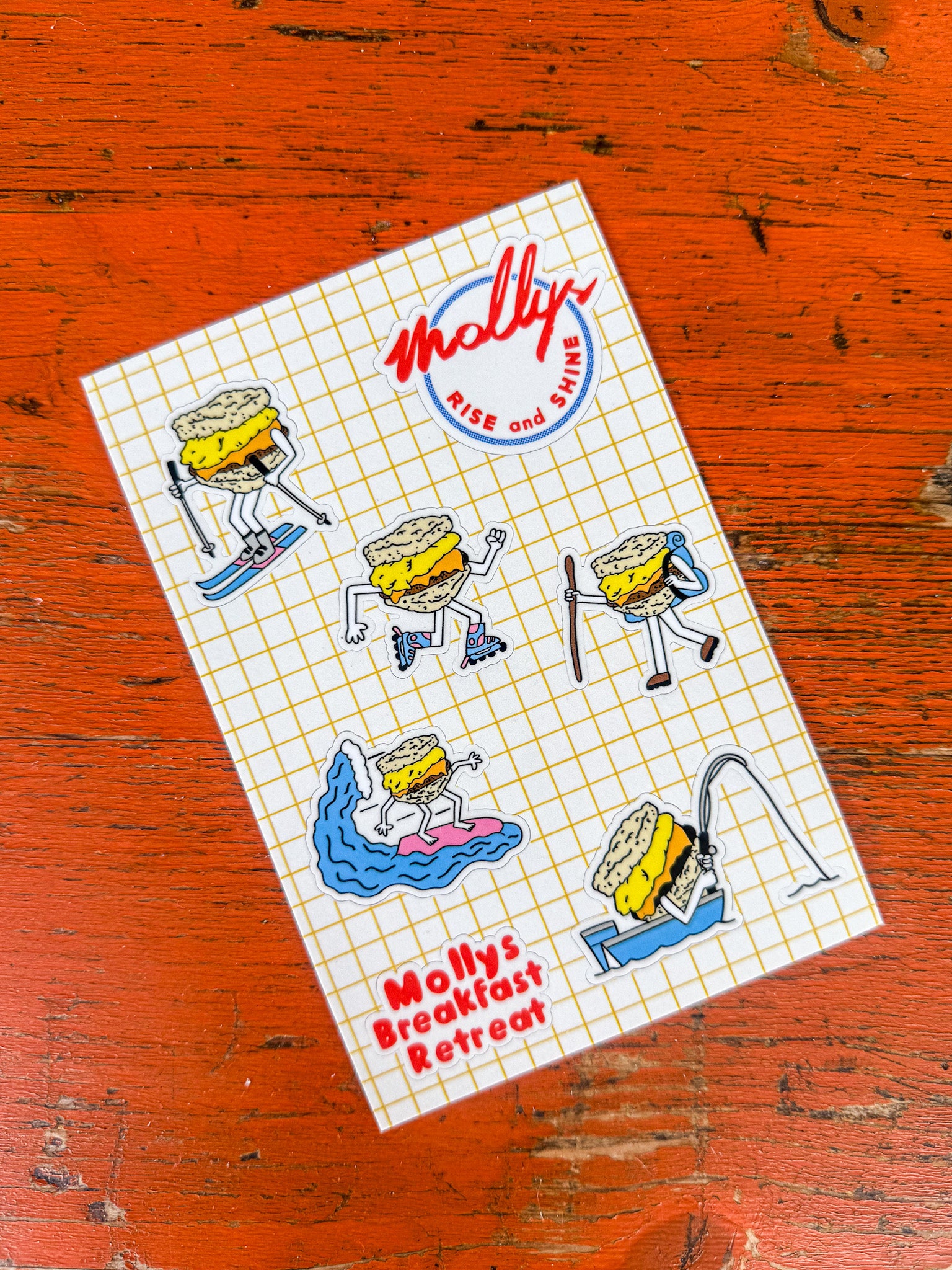 Sheet of stickers with cartoon biscuit characters and 'Molly's Breakfast Retreat' branding on a grid background.