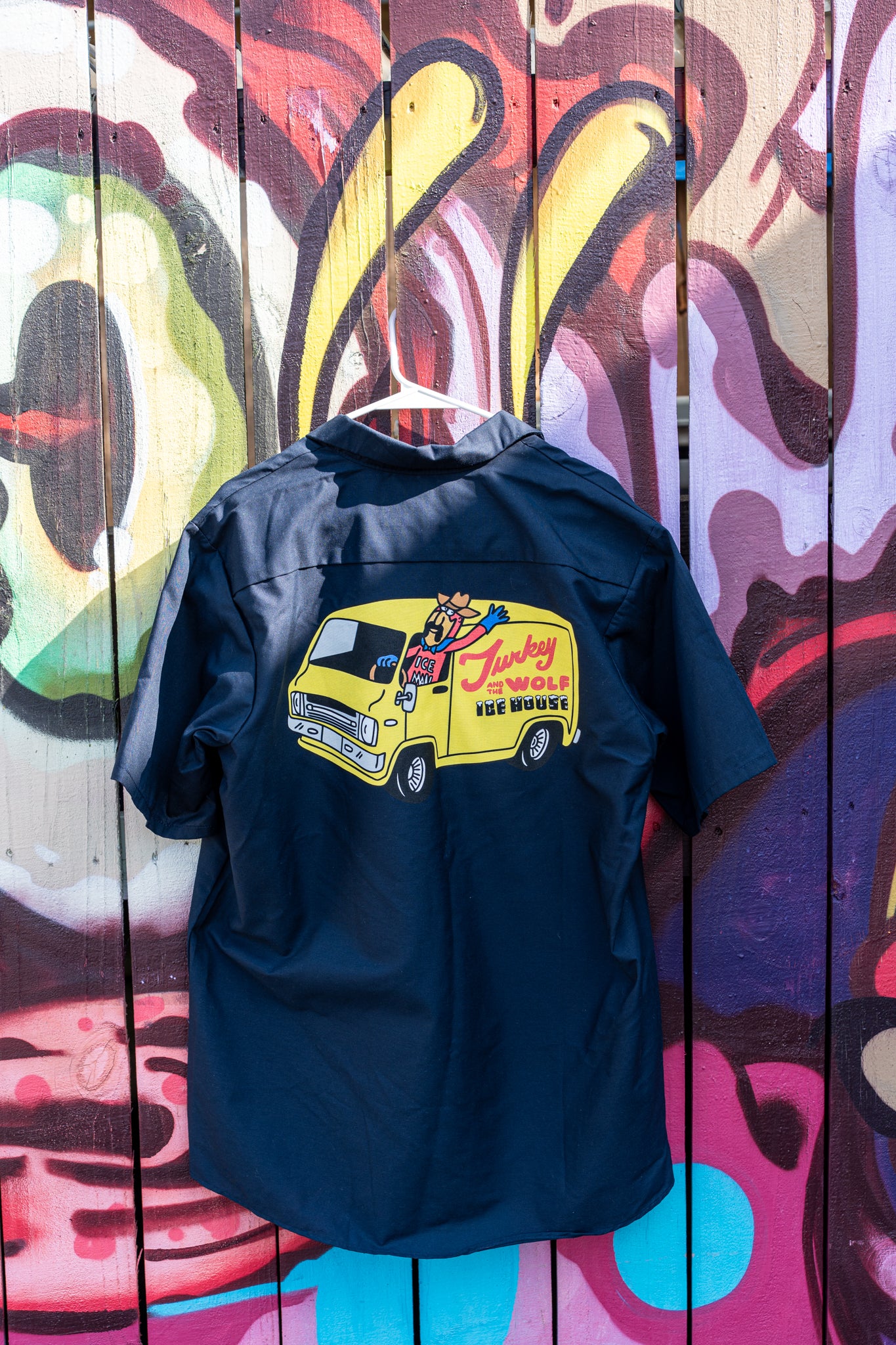 Black shirt with yellow truck graphic on a colorful wooden background